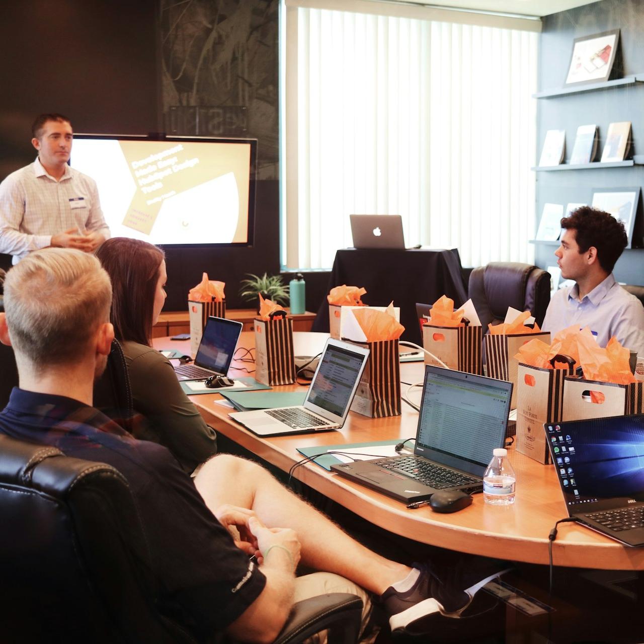 man standing in front of people sitting beside table with laptop computers